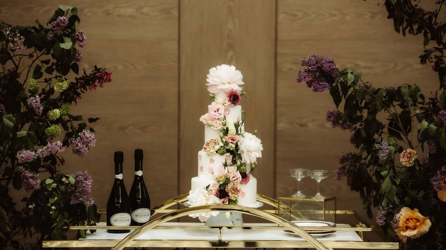 A platform with a tall cake, wine and wine glasses.