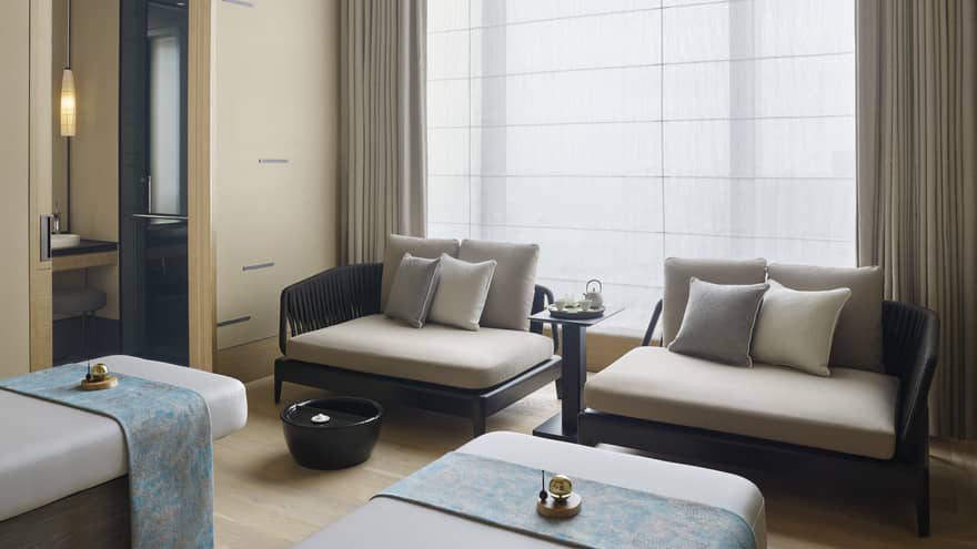 Couples Treatment Room, two spa treatment beds and small sofas under tall window