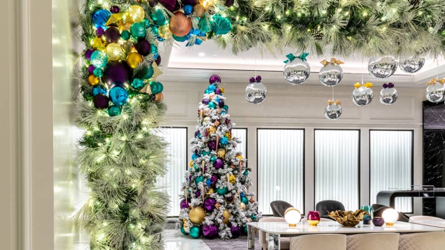 A Christmas tree in a room with table and chairs.