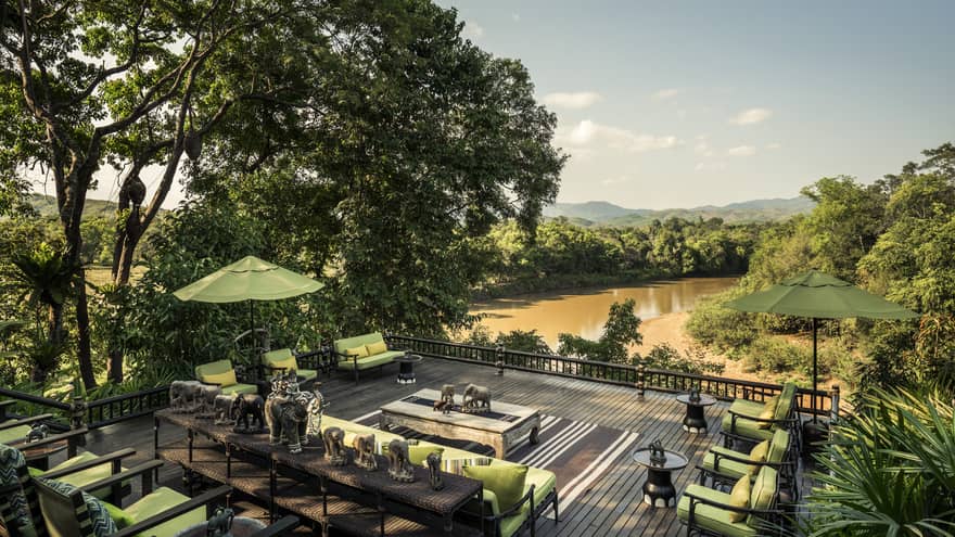 Terrace with plush patio chairs and elephant statuary overlooking the river at Four Seasons Tented Camp Golden Triangle
