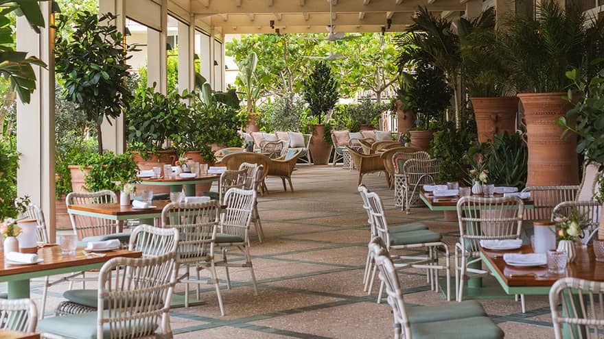 Restaurant terrace with sage green and white decor and live greenery