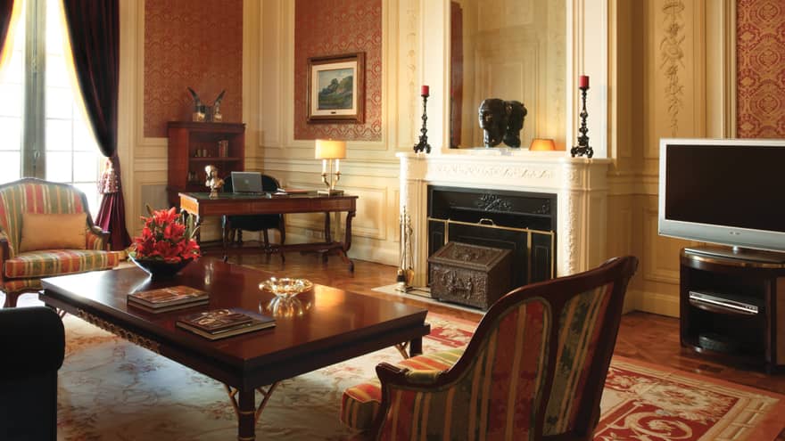 La Mansión Royale Suite living room with white fireplace mantel, dark wood furniture, Old World decor