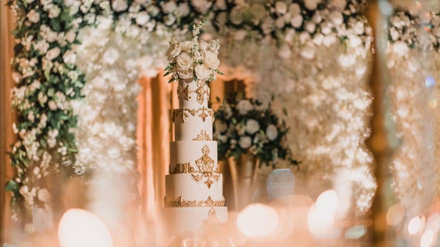 Wedding cake with multiple layers and flowers surrounding it.