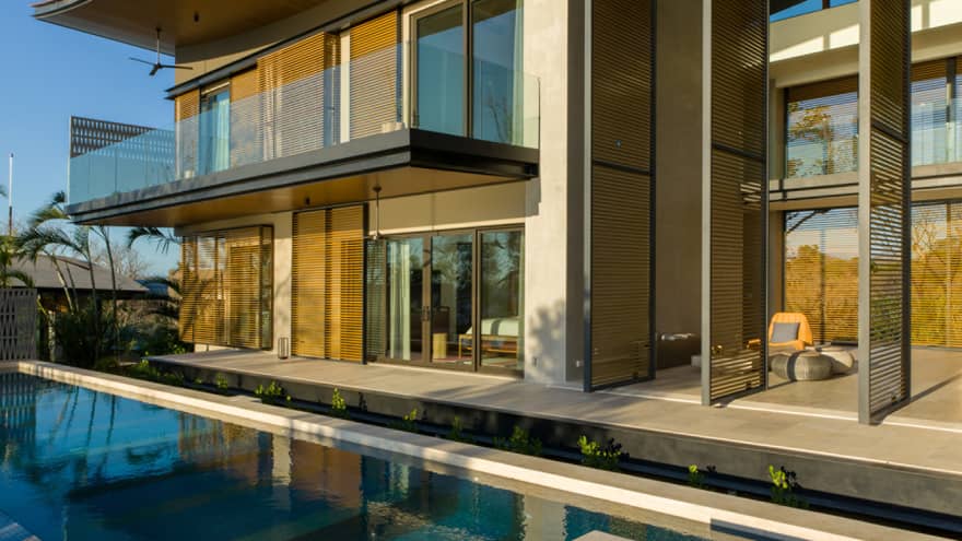 Two storey home with balcony beside an infinity pool