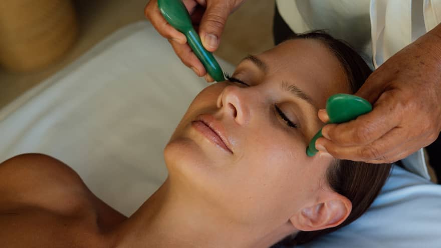 Guest getting a face massage while laying on a massage table.
