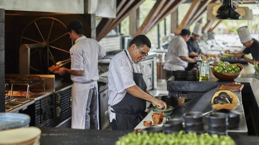 Chefs prepare food with ceramic and wooden dishes in a bustling kitchen