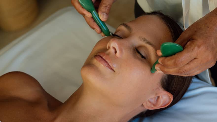 Guest getting a face massage while laying on a massage table.