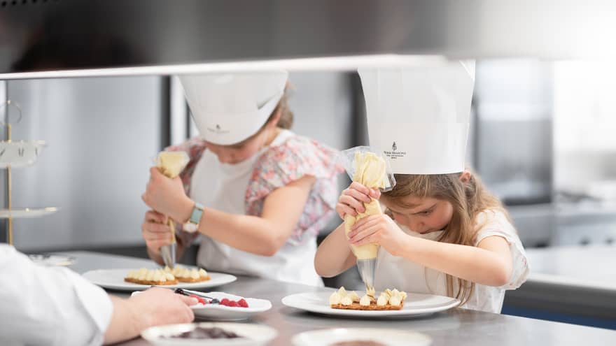 Children icing cooking while wearing chef hats.