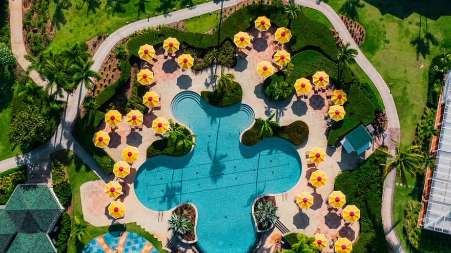 A birds eye view of a pool with yellow umbrellas around it.