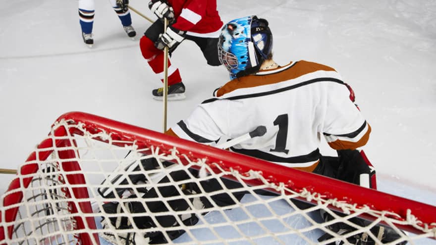 Back view of hockey goalie in net blocking goal