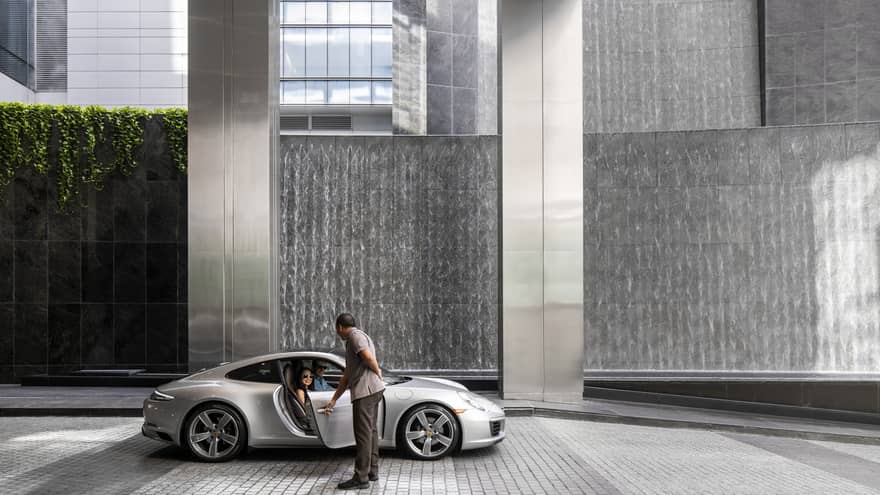 A hotel team member opening the door of a silver car.
