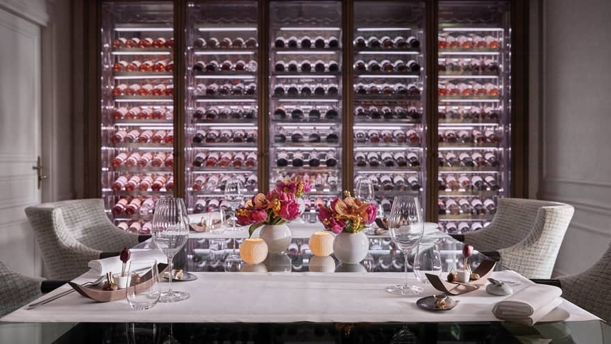 A private dining room with two chairs and an illuminated wall of wine on display