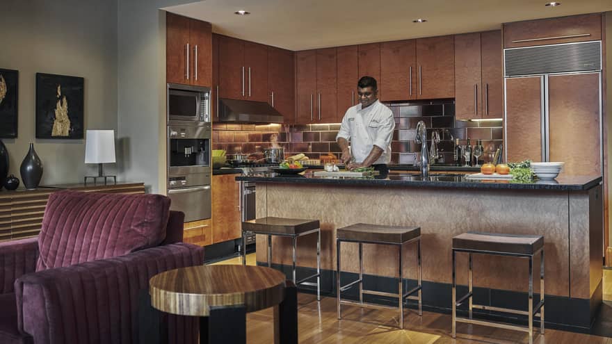 Chef prepares meal in kitchen that overlooks living room