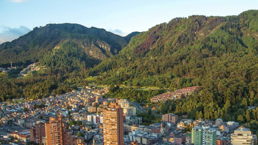Aerial view of Bogota city high rises, houses and dome sports field on sunny day