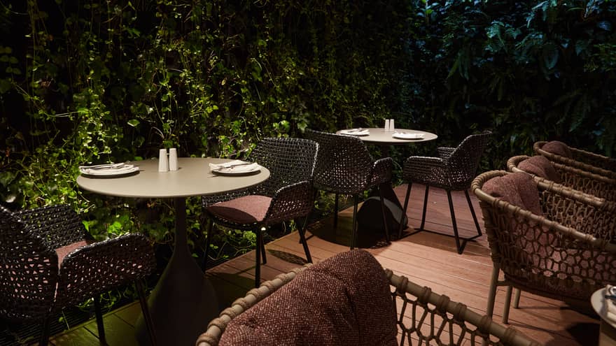Dimly lit restaurant terrace surrounded by walls of greenery