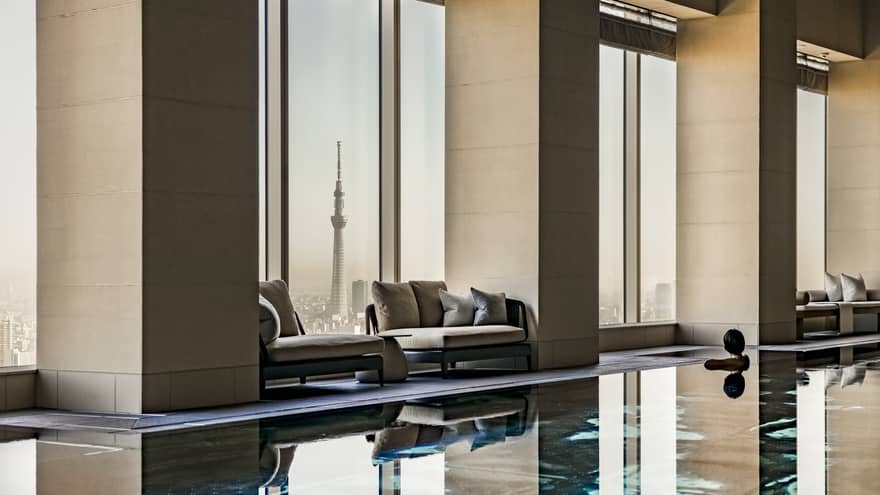 A spacious room with cushioned seats by the windows that have a clear view of the Tokyo Skytree and the surrounding city.
