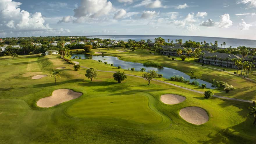 A bird's eye view of a golf course with sand pockets, water and trees.