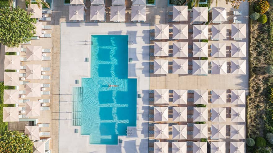 Aerial view of resort pool with five rows of umbrellas on one side and two rows on the other three sides