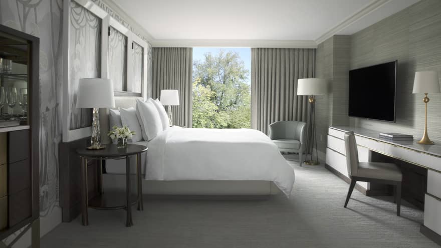 Garden Suite hotel room bed with white linens across from desk, tv 
