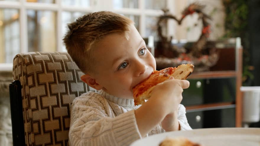 Young boy eats a slice of pizza