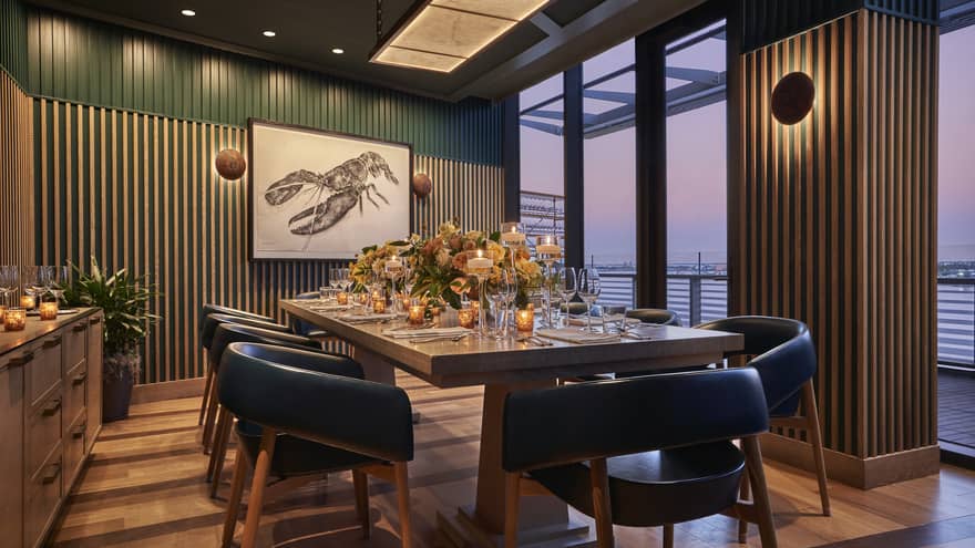 A private dining room with a large table, black chairs and large windows.