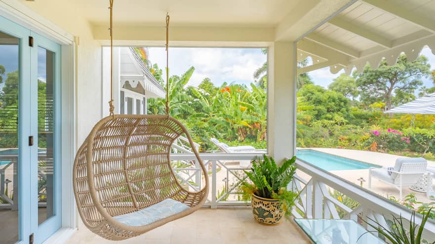 Covered outdoor terrace of a tropical residence, featuring a hanging rattan chair