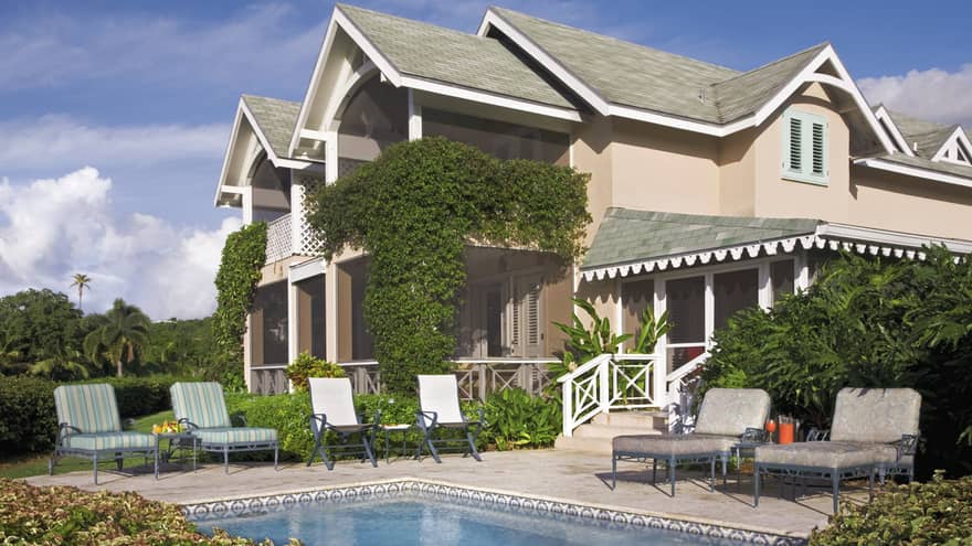 Palm Grove Residence exterior behind private pool, lounge chairs on deck