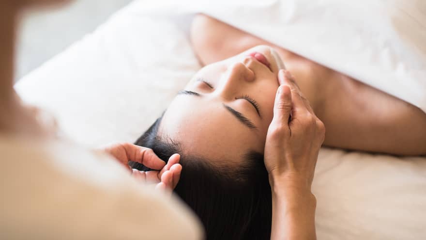 A guest receiving a soothing facial at a spa, lying on a massage table, surrounded by calming décor and soft lighting.