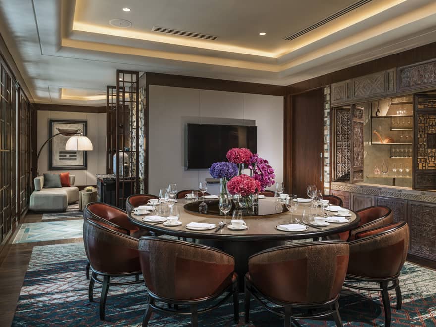 Leather bucket chairs around private meeting dining table, TV on wall
