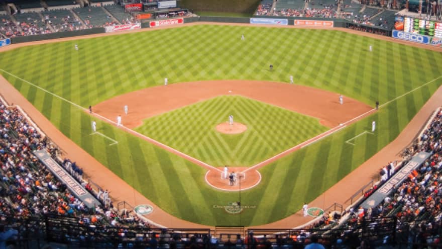 View over large open air baseball stadium with crowds in stands, city buildings in background