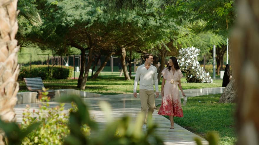 Couple walks along pathway surrounded by flora and fauna