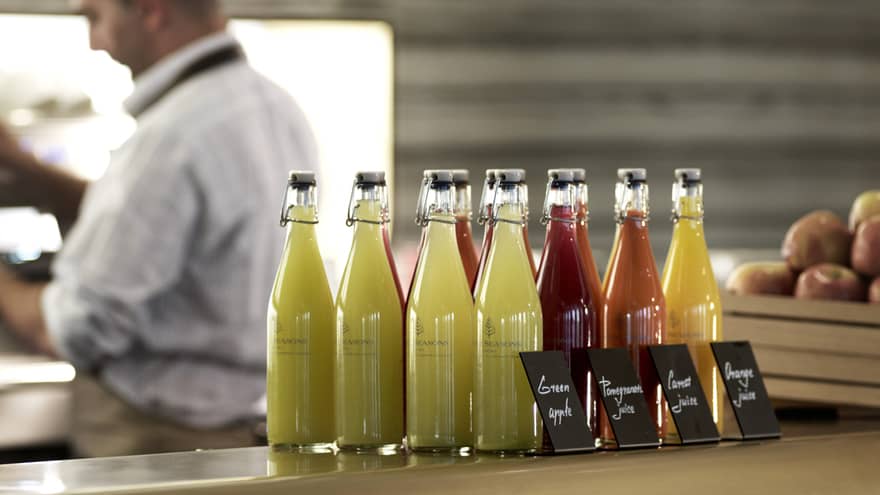 Several pressed juices sealed in glass jars on a countertop. 