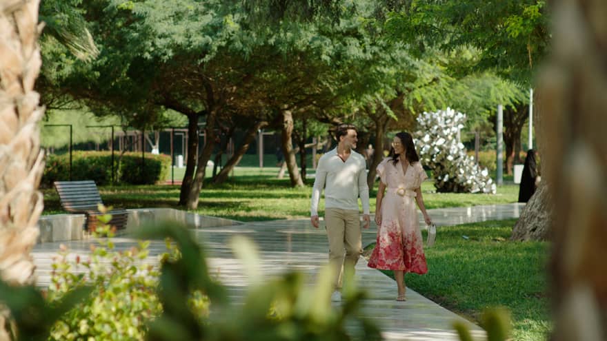 Couple walks along pathway surrounded by flora and fauna