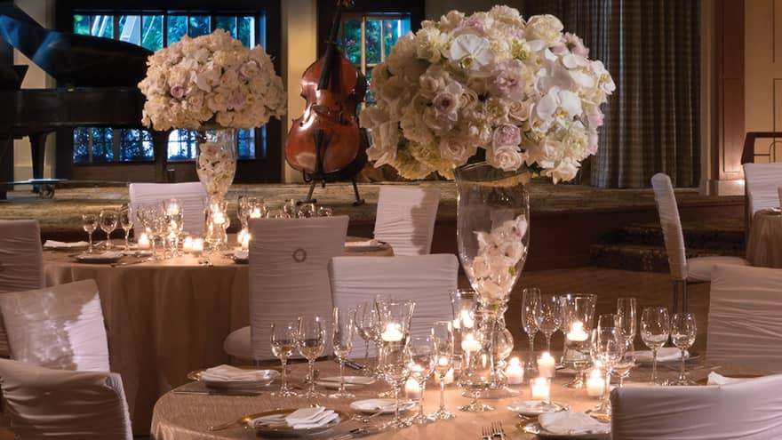 Elegant wedding reception tables with white chairs, flowers on ballroom floor