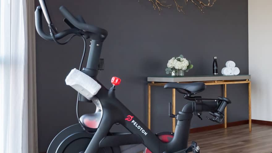 Peloton machine in a room with floor-to-ceiling windows on one wall.