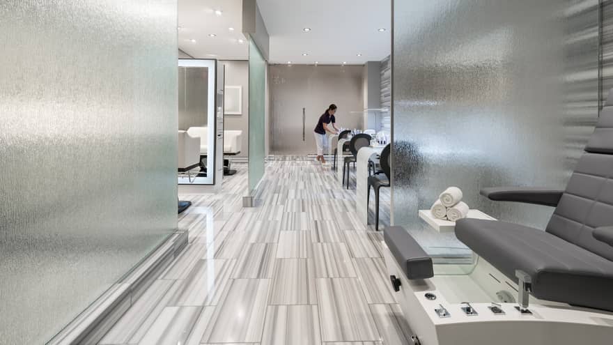 Spa staff sets up table in modern salon with frosted glass panels