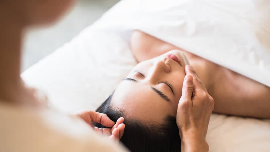 A guest receiving a soothing facial at a spa, lying on a massage table, surrounded by calming décor and soft lighting.