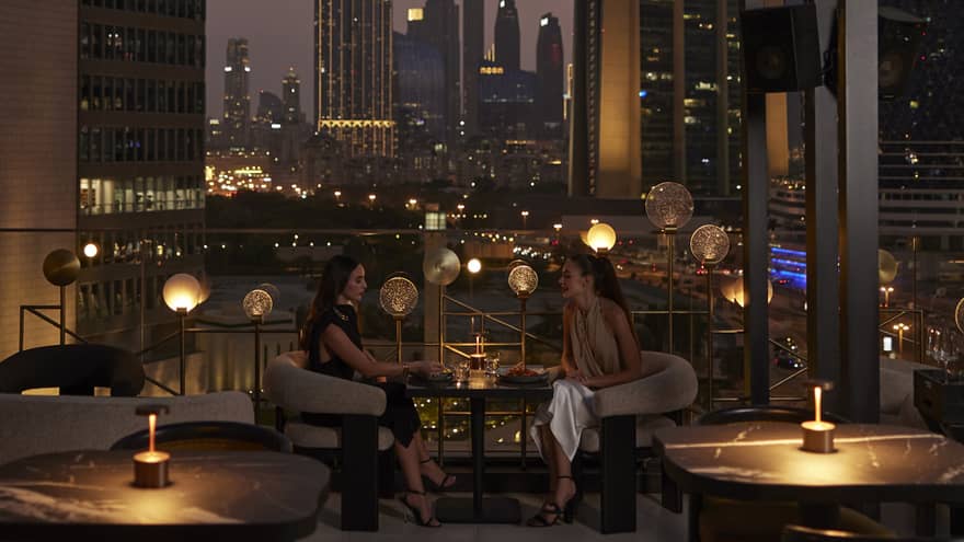 Nightime view of rooftop lounge with Dubai skyline in background