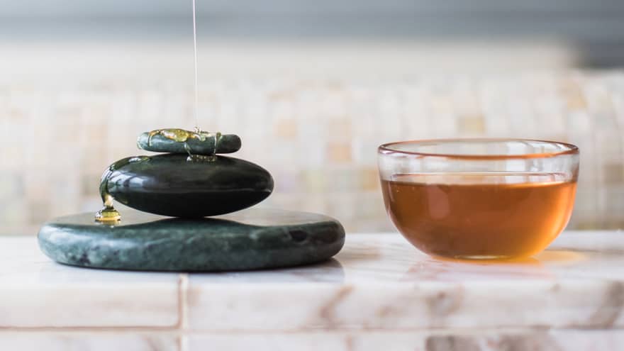 Royal Moroccan Hammam, honey drizzled on stack of black stones next to bowl of honey