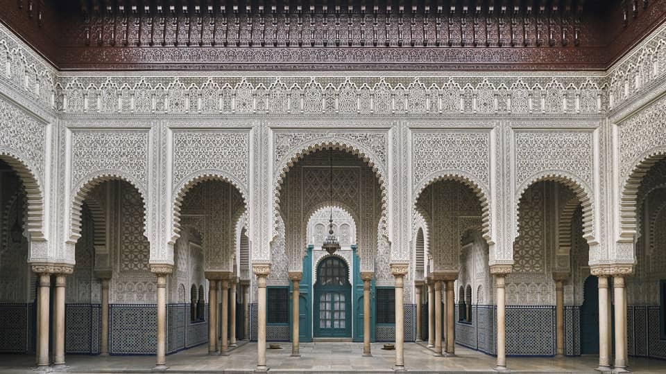 An ancient building with turquoise carved wooden doorways and Moorish influences