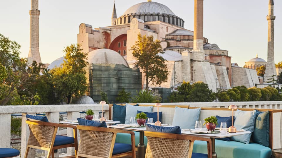 Terrace with outdoor table and blue cushioned chairs and the Blue Mosque in the background