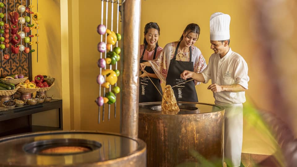 Chef teaches two female guests during Indian cooking class at Baraabaru