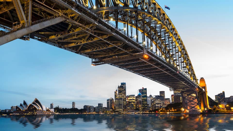 View from under bridge to Sydney waterfront skyline, lights at dusk