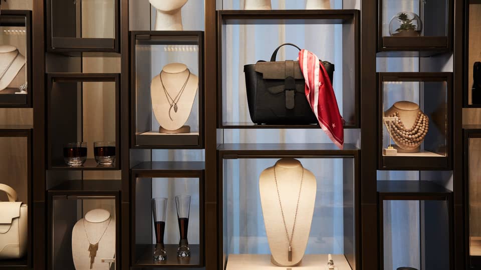 Boutique retail store shelf with designer necklaces, handbag, cocktail glasses 