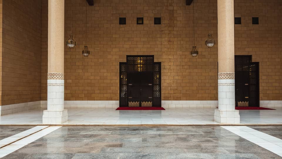 A brown stone wall with grey tile flooring.