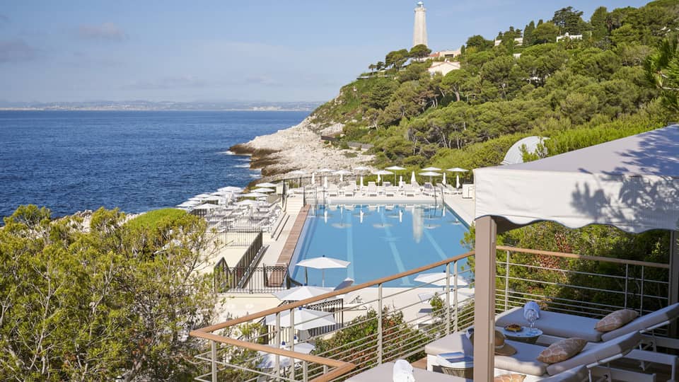 View from terrace of Club Dauphin pool, Mediterranean, green hillside and lighthouse