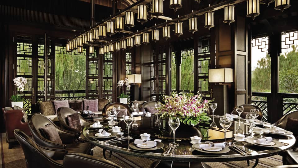 Large round, black, shiny dining table under lantern chandelier at Jin Sha