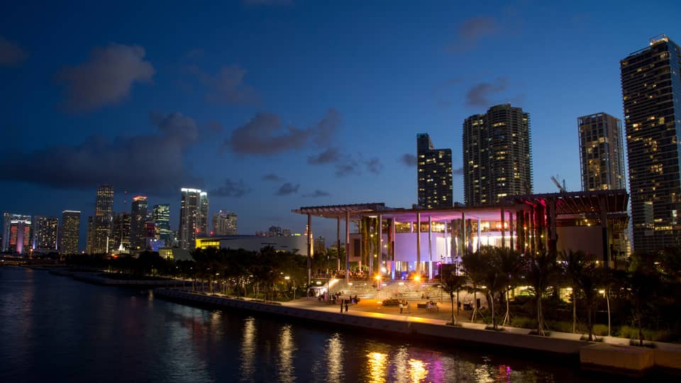 Building with colourful lights at night along water 