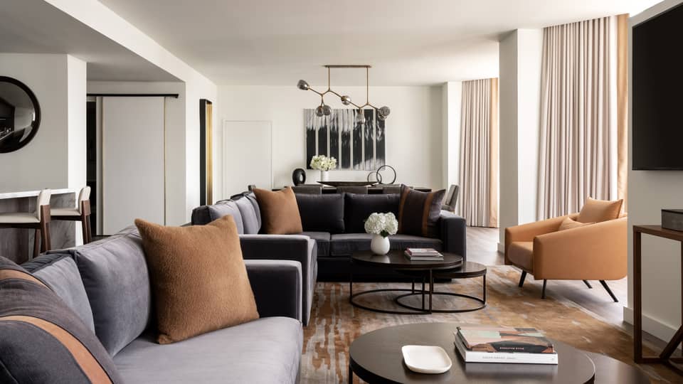 Living room with two grey-blue velvet sofas, tan leather arm chairs, round metal coffee table