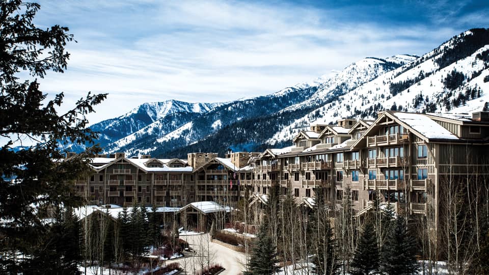 the exterior of the hotel is covered in snow and surrounded by snow capped mountains 